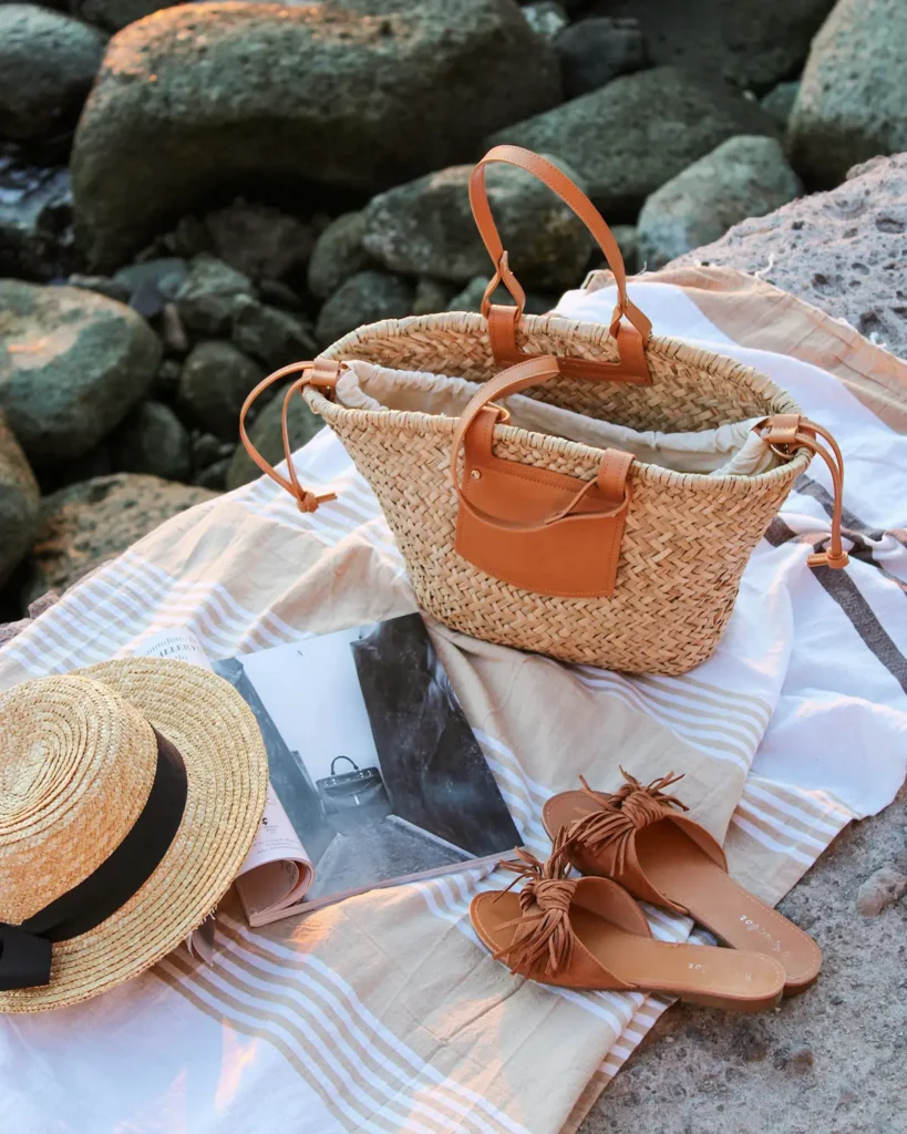Summer accessories with straw bag, hat and sandals by the sea
